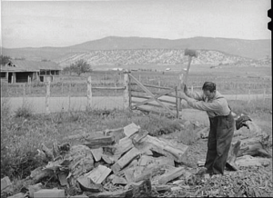 A sepia photograph of a man chopping wood.